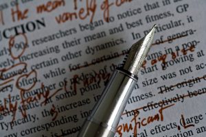 A nib pen resting on paper with text and red editing marks.