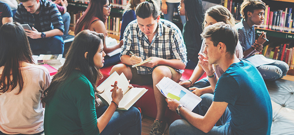 Students sitting in a group with textbooks open on their laps.